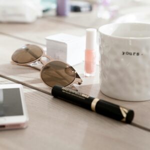 Modern summer essentials like sunglasses and coffee mug on a wooden table. Cozy and stylish setting.